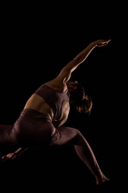 Yoga pozu veren zinde bir kadın. Stüdyoda siyahlara karşı egzersiz yapan yarım siluet kız..