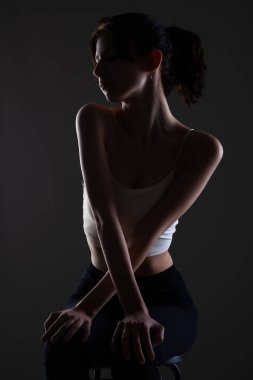 Stüdyoda karanlık arka planda güzel bir genç kızın yarım siluet portresini aydınlattım..