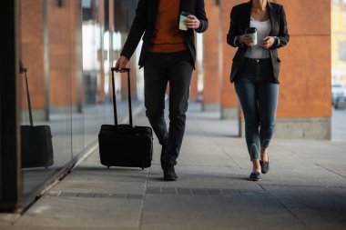 İş adamı ve kadın kahve içiyor. İş adamları bavullarıyla birlikte seyahat ediyorlar.