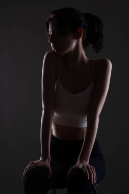 Stüdyoda karanlık arka planda güzel bir genç kızın yarım siluet portresini aydınlattım..