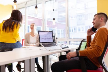Modern bir ofis alanında masaüstü ve dizüstü bilgisayarlar üzerinde çalışan yaratıcı gençler takımı.