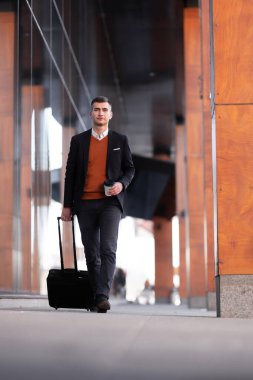 İş adamı yürüyor ve kahve içiyor. Tramvay bagajlı bir adam.