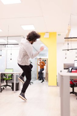 Ofiste eğlenen iki iş adamı. Dost canlısı meslektaşlar atlayıp dans ederek başarıyı kutluyor.