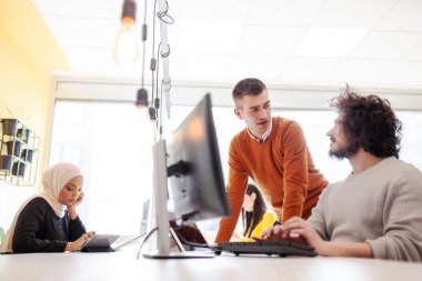 İş adamları bilgisayarın önünde sohbet ediyorlar. Modern çok ırklı ofis alanı. 