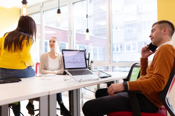 Modern bir ofis alanında masaüstü ve dizüstü bilgisayarlar üzerinde çalışan yaratıcı gençler takımı.