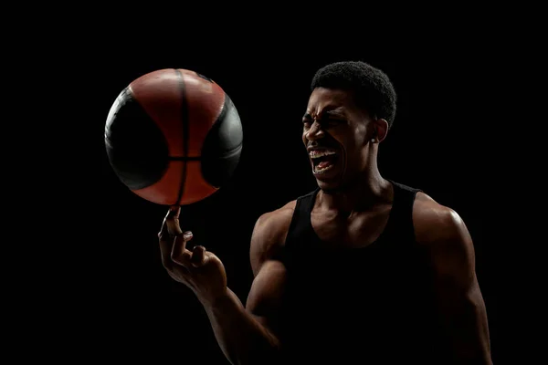 篮球运动员在黑色背景下旋转着一个球 尖叫的非洲裔美国人轮廓 — 图库照片