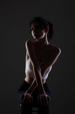 Stüdyoda karanlık arka planda güzel bir genç kızın yarım siluet portresini aydınlattım..