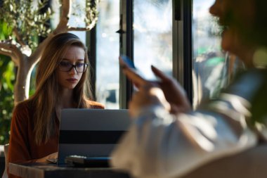 Bir kafede iki genç iş kadını teke tek görüşüyor. İşten sonra arkadaşlar dedikodu yapar ve güneşli bir günde cam kenarında kahve içerler..