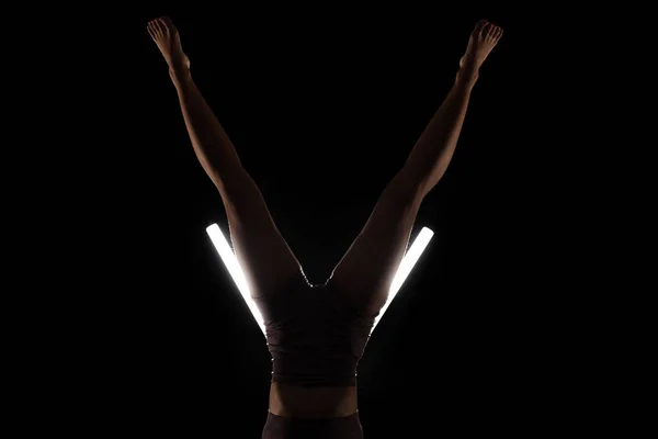ヨガのポーズを練習する女性にフィット シルエットの女の子はV字型の白い鉛管光で黒の背景にスタジオで運動をしています ストレスのないインナーバランスのコンセプト — ストック写真