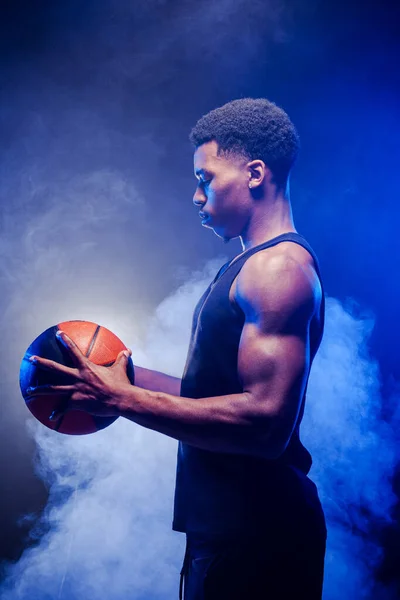 Basketbal Hráč Svítí Modrou Barvou Drží Míč Proti Kouři Pozadí — Stock fotografie