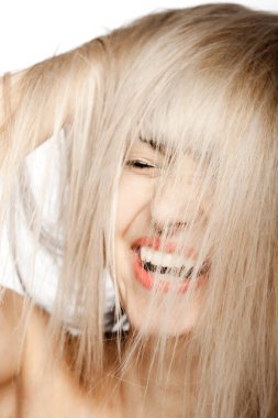 Sarışın, püsküllü güzel bir esmer kızın portresi. Düşen saçların ardından gülümseyen mutlu yüz ifadesi.