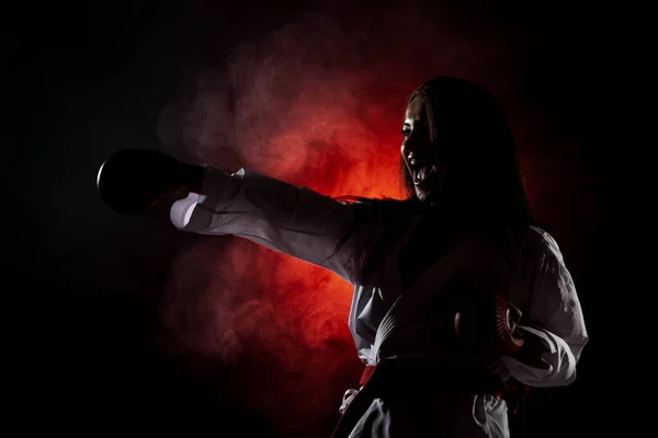 在红色雾气背景下练习空手道拳的漂亮女孩 — 图库照片