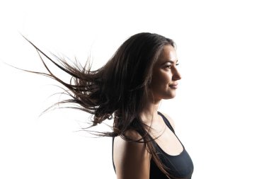 Beyaz arka planda dalgalı saçları olan güzel esmer bir kızın stüdyo portresi..