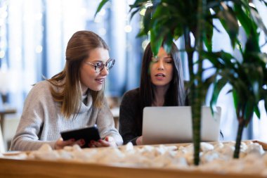 Bir kafede iki kız ve bir tablet ve dizüstü bilgisayar.