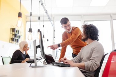 İş adamları bilgisayarın önünde sohbet ediyorlar. Modern çok ırklı ofis alanı. 