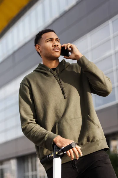 Молодой Африканский Американец Повседневной Одежде Стоит Электрическим Скутером Разговаривает Телефону — стоковое фото