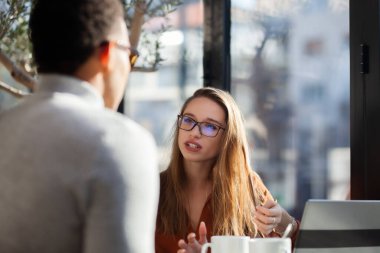 Friends in a restaurant talking smiling and drinking tea. Business colleagues having a meeting after work or during coffee break at a cafe bar.