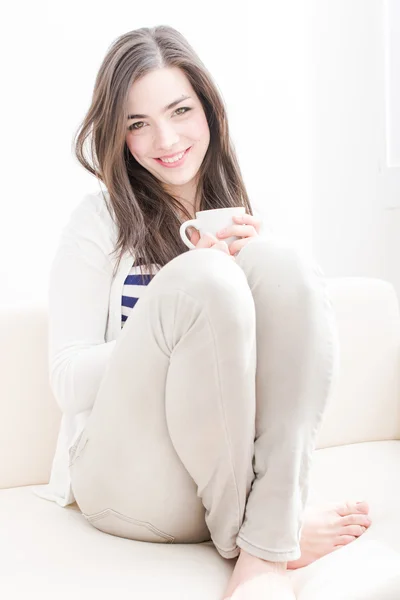 有魅力的年轻女人在沙发上喝咖啡 — 图库照片