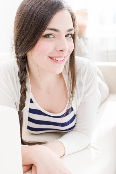 Jovem mulher relaxante e sorrindo em casa — Fotografia de Stock