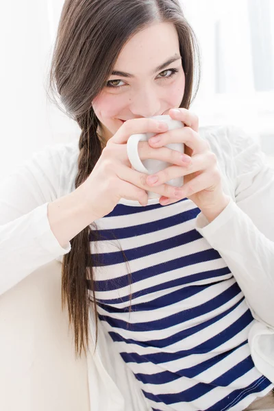 Ελκυστική νεαρή γυναίκα που πίνει καφέ στο καναπέ — Φωτογραφία Αρχείου