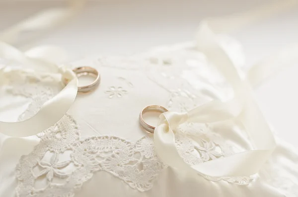 Anillos de boda dorados en pequeño cojín blanco — Foto de Stock