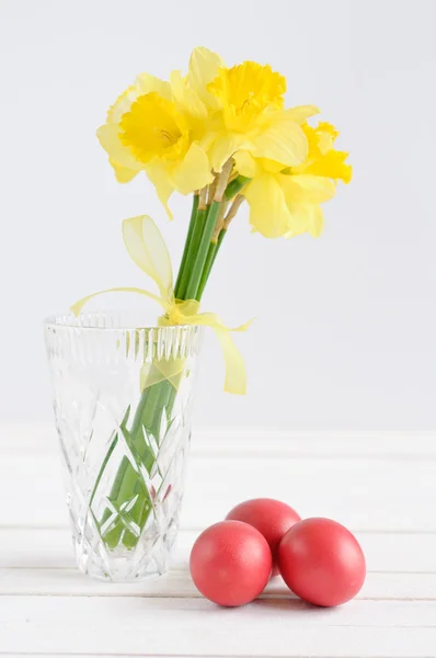 Spring flowers with easter eggs on white wooden background — Stock Photo, Image