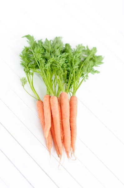 Grappolo di carote arancioni con foglie verdi isolate su bianco — Foto Stock