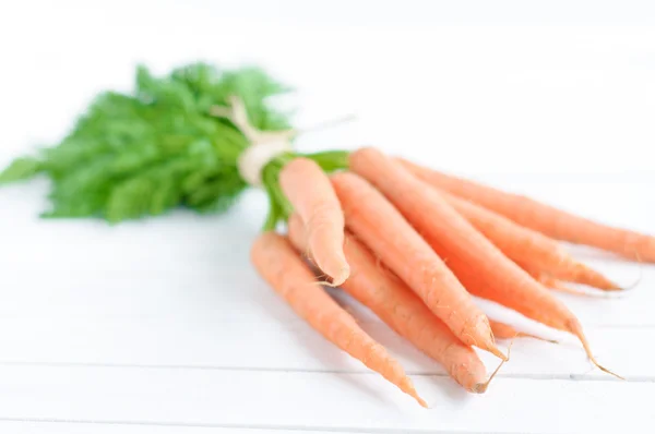 Grappolo di carote arancioni con foglie verdi isolate su bianco — Foto Stock