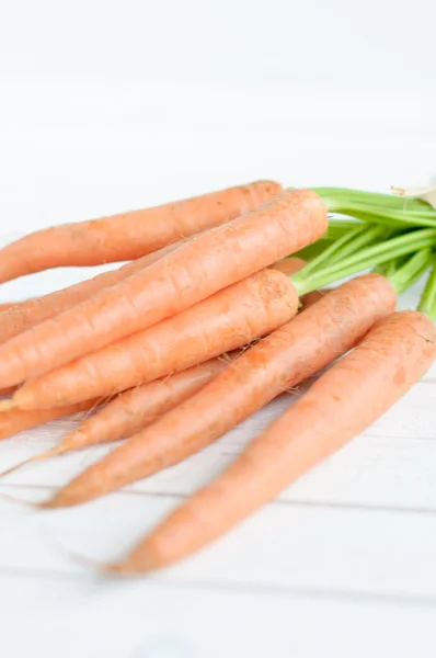 Gäng orange morötter med gröna blad isolerade över vita — Stockfoto