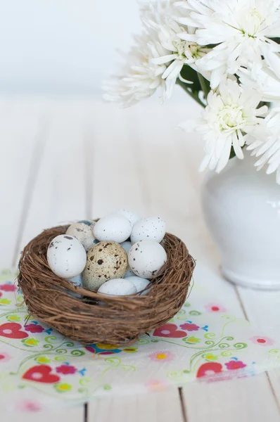 Different types of eggs in a nest on a white wooden background — Stock Photo, Image