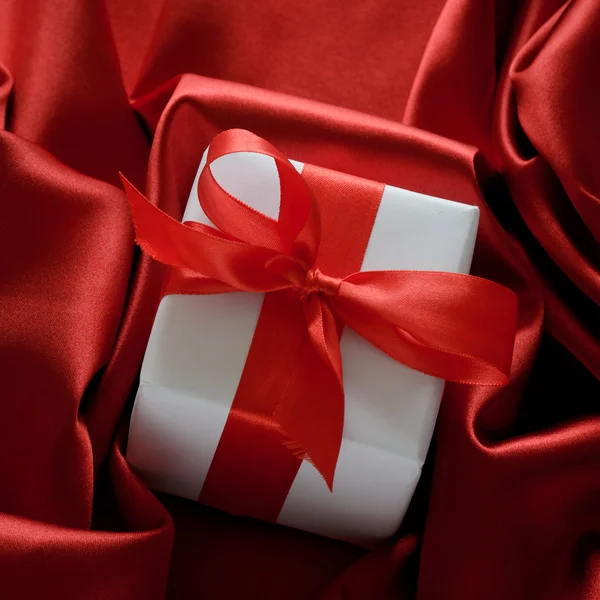 Valentines boîtes-cadeaux attachées avec un ruban de satin rouge noeud sur fond de satin rouge — Photo