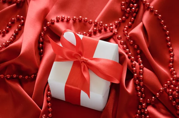 Valentines boîtes-cadeaux attachées avec un ruban de satin rouge noeud sur fond de satin rouge — Photo