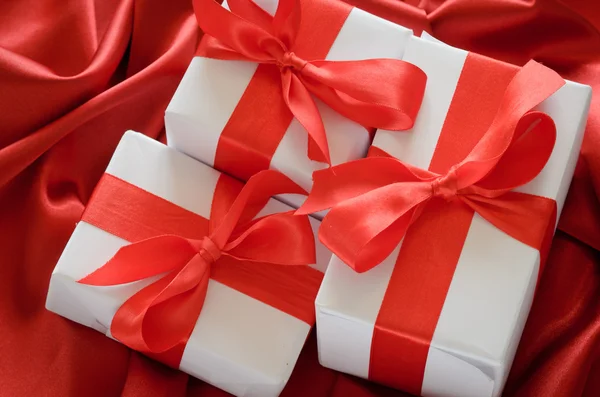 Valentines gift boxes tied with a red satin ribbon bow on red satin background — Stock Photo, Image