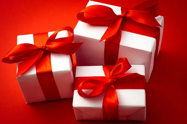 Подарункові коробки Валентина прив'язані червоним атласною стрічкою на червоному атласному фоні — стокове фото