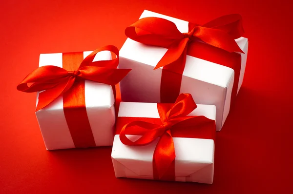 Valentines gift boxes tied with a red satin ribbon bow on red satin background — Stock Photo, Image