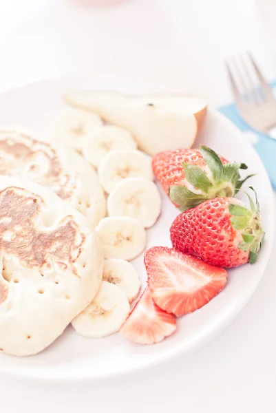 Leckere Pfannkuchen am Frühstückstisch mit Früchten — Stockfoto