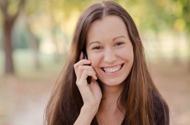genç gülümseyen kadın cep telefonuyla konuşuyor..