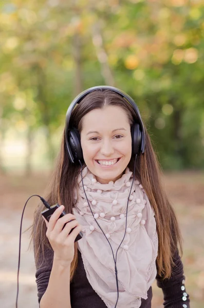 Hübsche junge lächelnde Frau hört Musik — Stockfoto