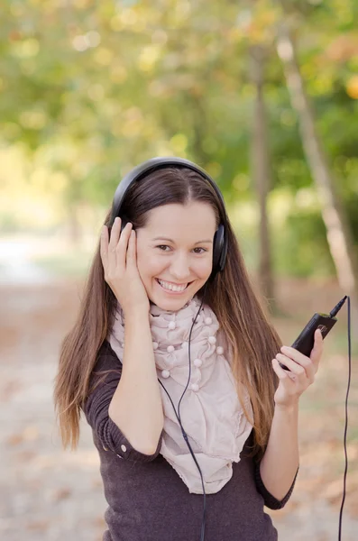 Hübsche junge lächelnde Frau hört Musik — Stockfoto