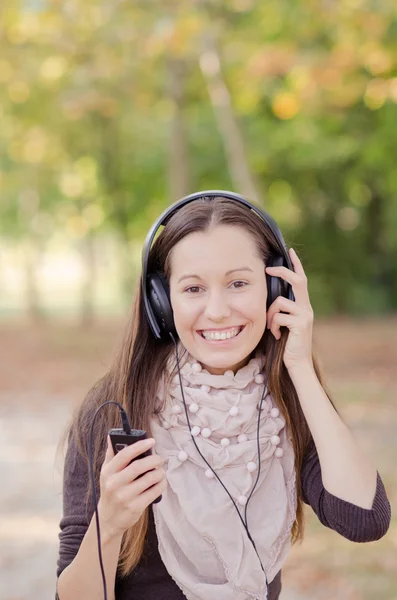 Pretty young smiling woman listening music — Stock Photo, Image