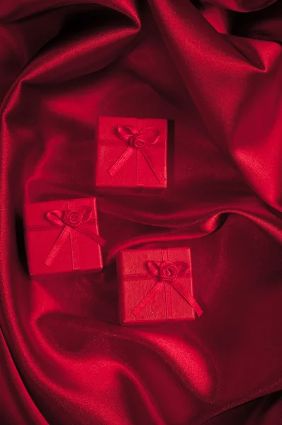 Valentines caixas de presente amarrado com um laço de fita de cetim vermelho no fundo de cetim vermelho — Fotografia de Stock