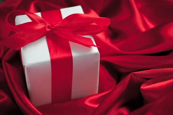 Valentines gift boxes tied with a red satin ribbon bow on red satin background — Stock Photo, Image