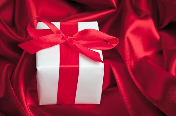 Valentines caixas de presente amarrado com um laço de fita de cetim vermelho no fundo de cetim vermelho — Fotografia de Stock