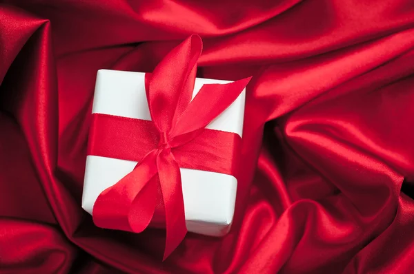Cajas de regalo de San Valentín atadas con un lazo de cinta de satén rojo sobre fondo de satén rojo —  Fotos de Stock