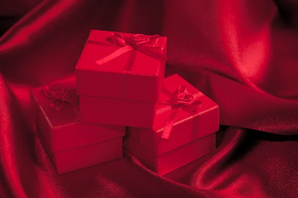 Valentines caixas de presente amarrado com um laço de fita de cetim vermelho no fundo de cetim vermelho — Fotografia de Stock