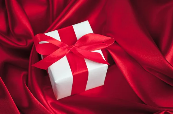 Valentines gift boxes tied with a red satin ribbon bow on red satin background — Stock Photo, Image