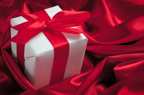 Valentines gift boxes tied with a red satin ribbon bow on red satin background — Stock Photo, Image