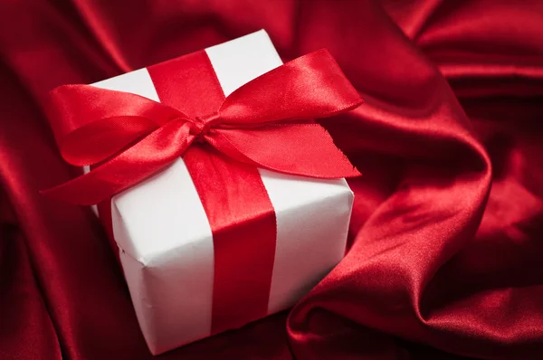 Valentines gift boxes tied with a red satin ribbon bow on red satin background — Stock Photo, Image