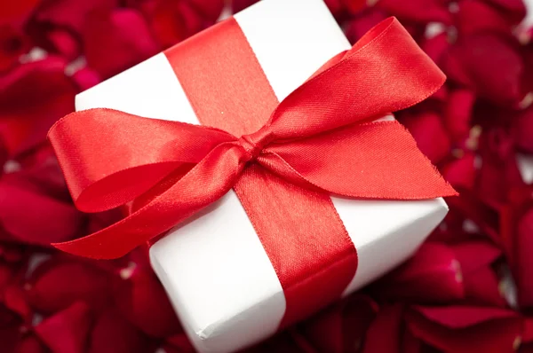 Geschenkbox über roten bunten Rosenblättern — Stockfoto