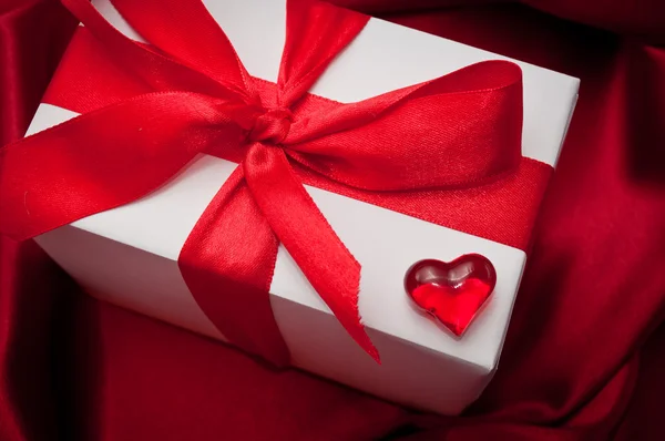Του Αγίου Βαλεντίνου δώρο κουτιά δεμένα με μια κόκκινη σατέν κορδέλα τόξο σε κόκκινο φόντο σατέν — Φωτογραφία Αρχείου